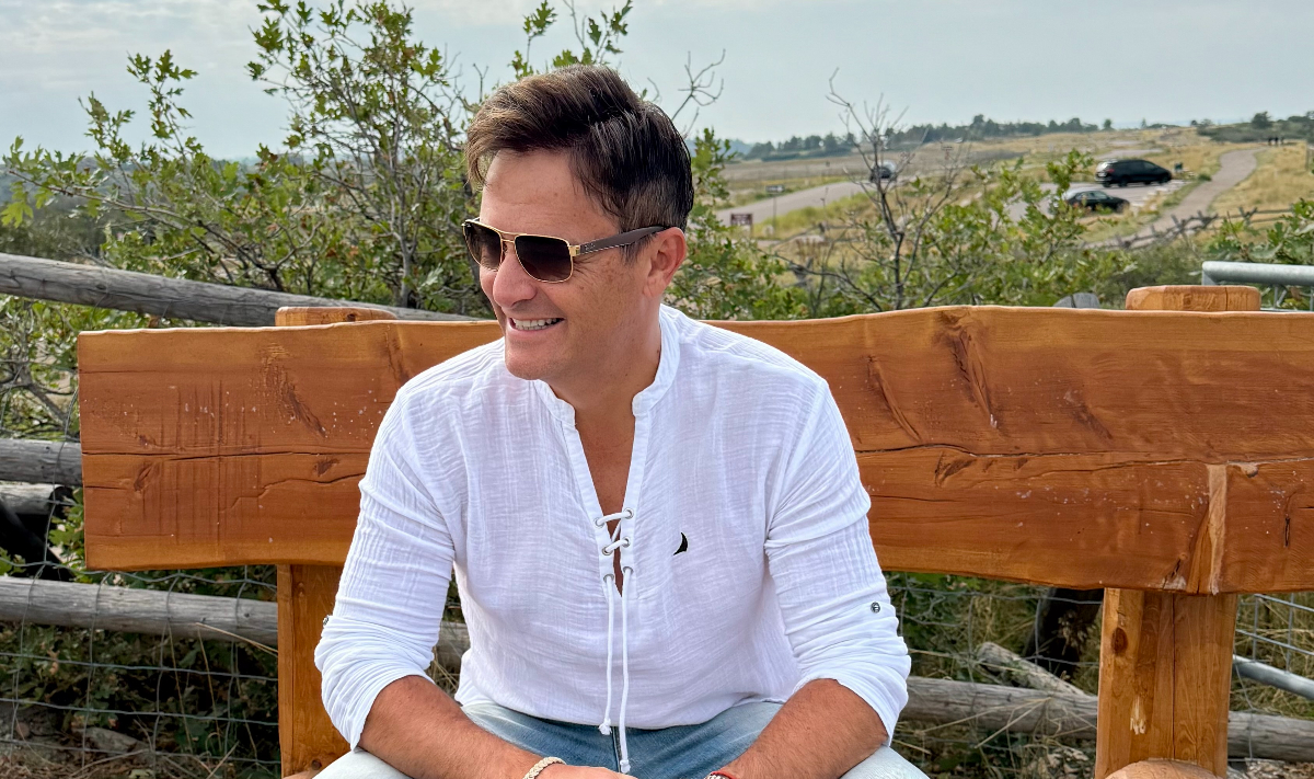 ARGYRO seated outdoors in sunglasses and a white shirt