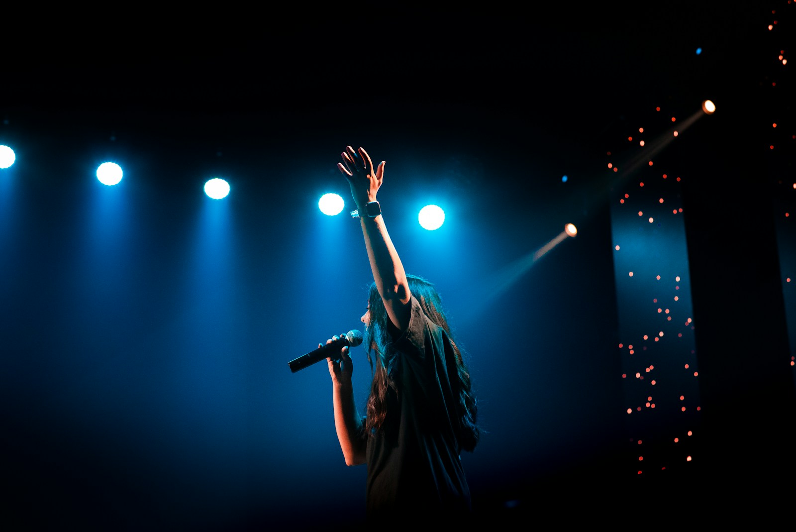Guitarist performing beside a microphone on a dark concert stage