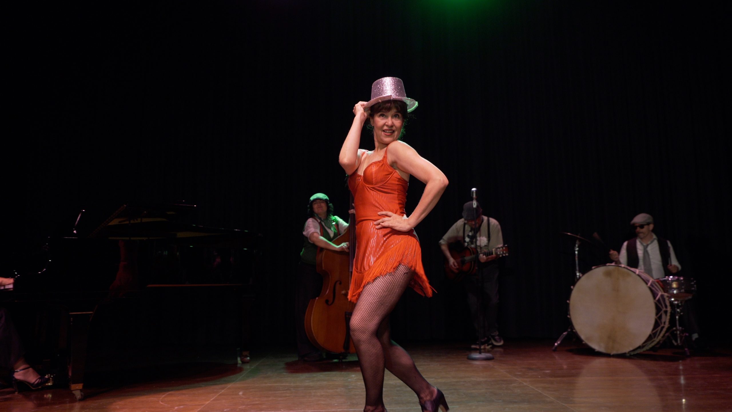 Isabela Ruiz performing in the Mis dos mitades film scene, with Doctor Seco and the ensemble