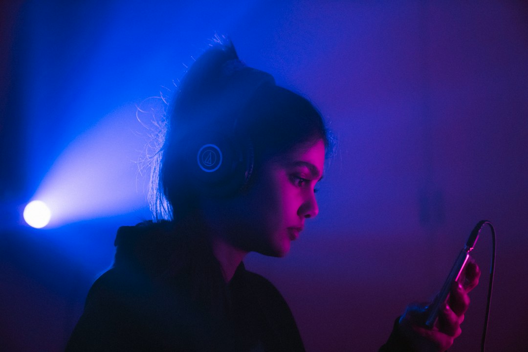Music listener illuminated by blue light while using headphones