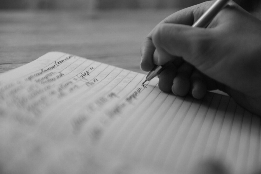 Songwriter writing in a notebook, image from The Mechanical Licensing Collective